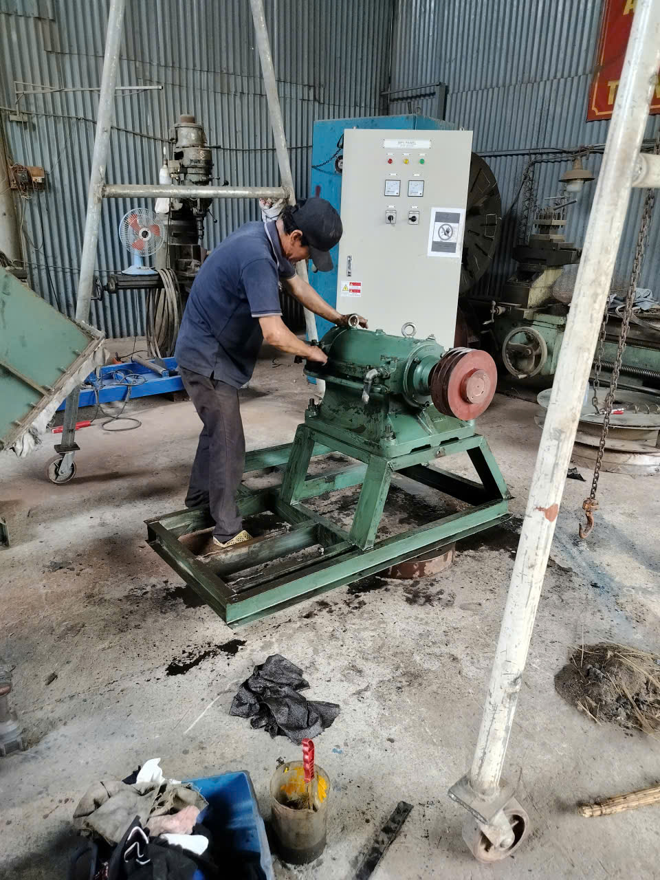 Người thợ đang làm việc bên máy màu xanh tại xưởng